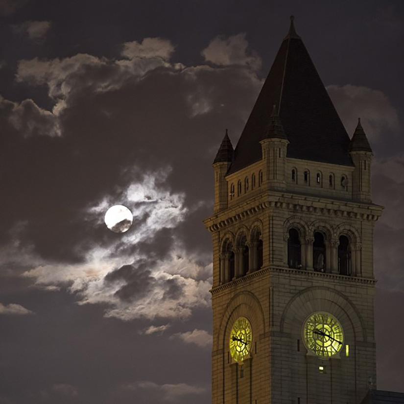 Image of a supermoon with a clock tower and clouds.