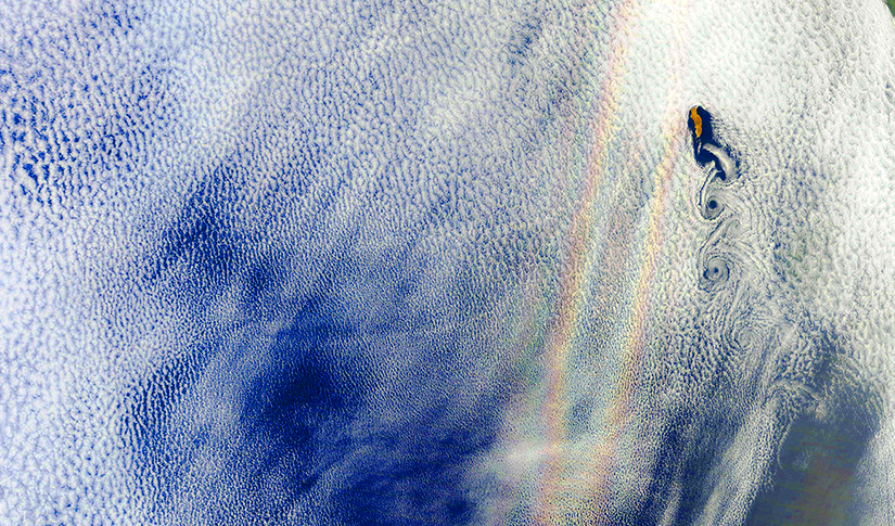 Clouds from space with a rainbow among them.  