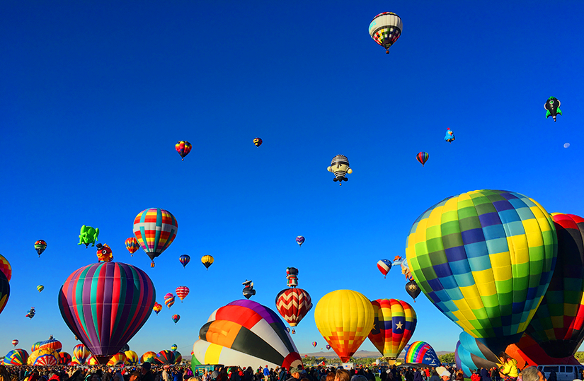 Hot air balloons of different sizes fill the sky.