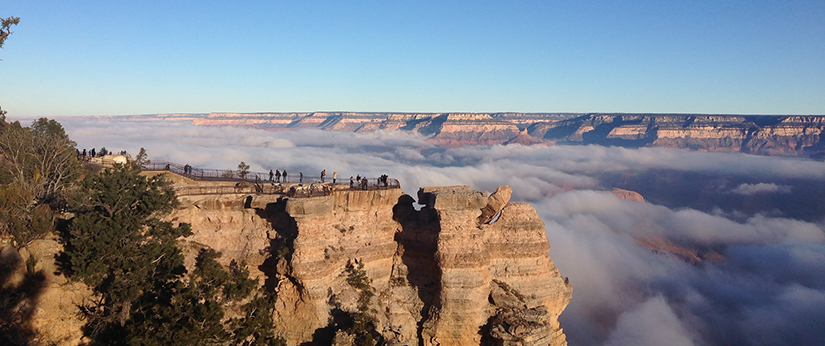 Fog within the Grand Canyon with people looking at it.