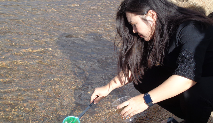 A woman kneels near water.