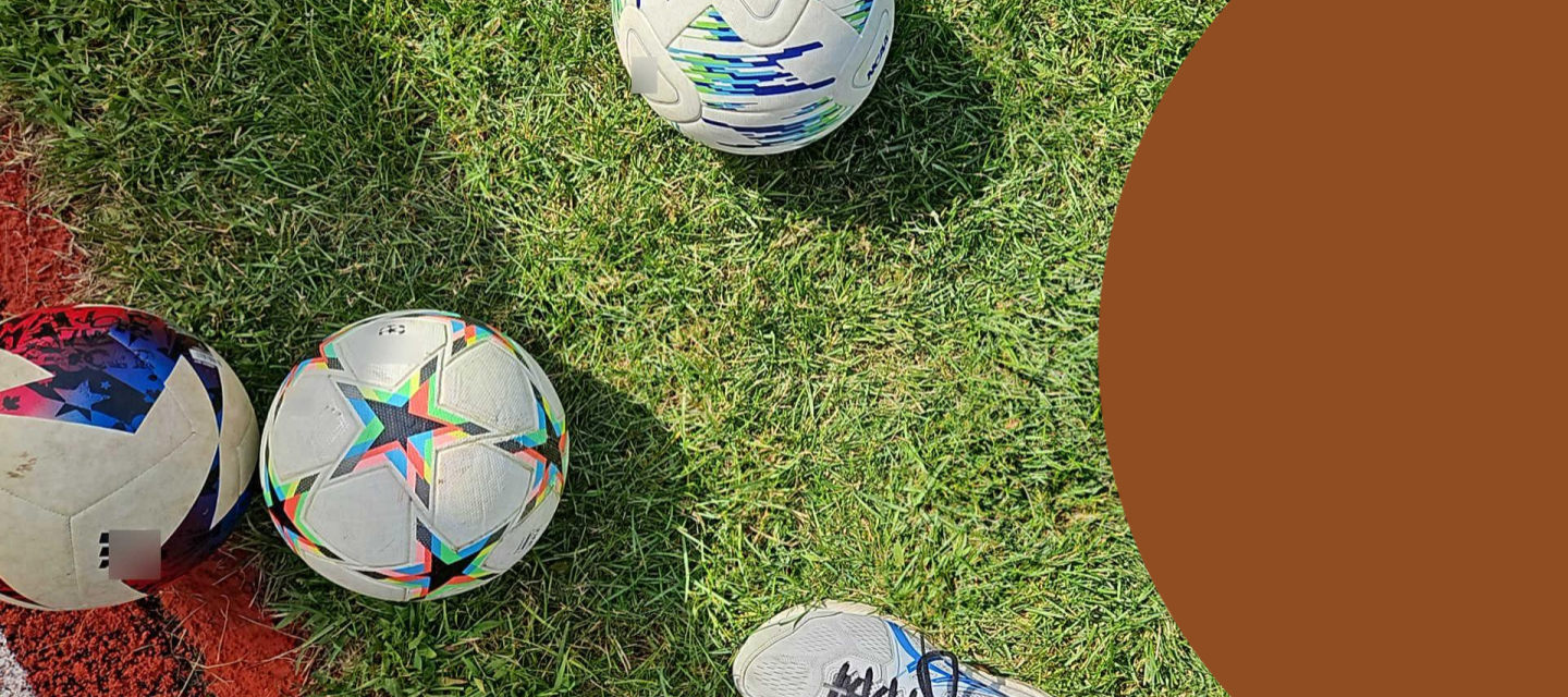 Three soccer balls (footballs) and a shoe on a green field.