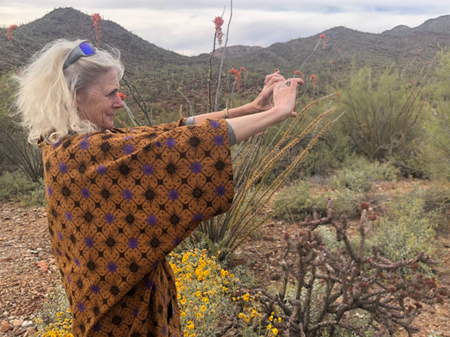 A woman uses a smart device to take a picture of the landscape.