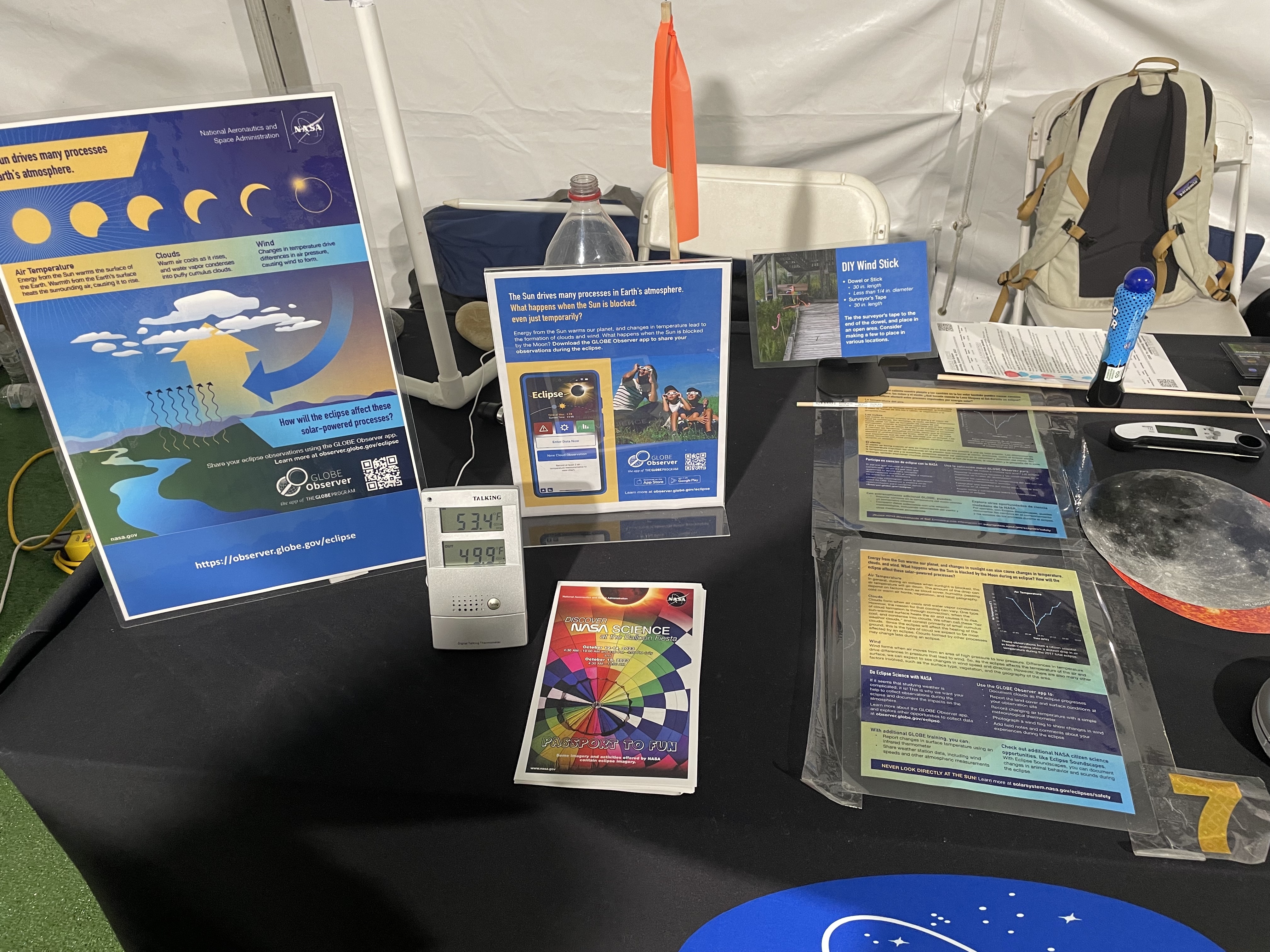 A tabletop display showing the GLOBE Eclipse atmosphere one-pager and GLOBE tabletop signs, a thermometer, solar viewing glasses, and a Sun and Earth cut out.