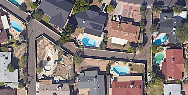 High resolution real-color satellite view of a suburban neighborhood with backyard pools.