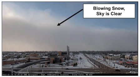 A landscape with blowing snow on the horizon and part of the sky clear.