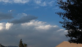 A roof line with clouds in the background.