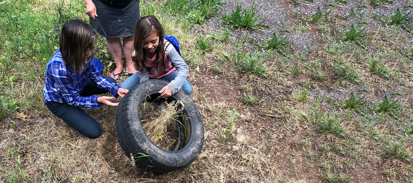 Two girls inspecting a discarded tire