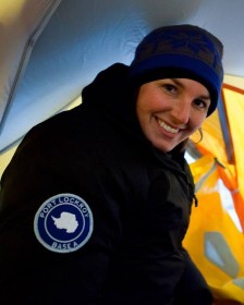 Scientist smiling in a tent in warm clothing.