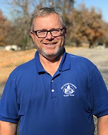 A middle-aged white man with light-colored hair and glasses, wearing a blue GLOBE polo shirt.