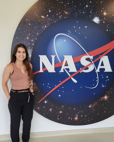Ashlee Autore stands in front of the NASA logo
