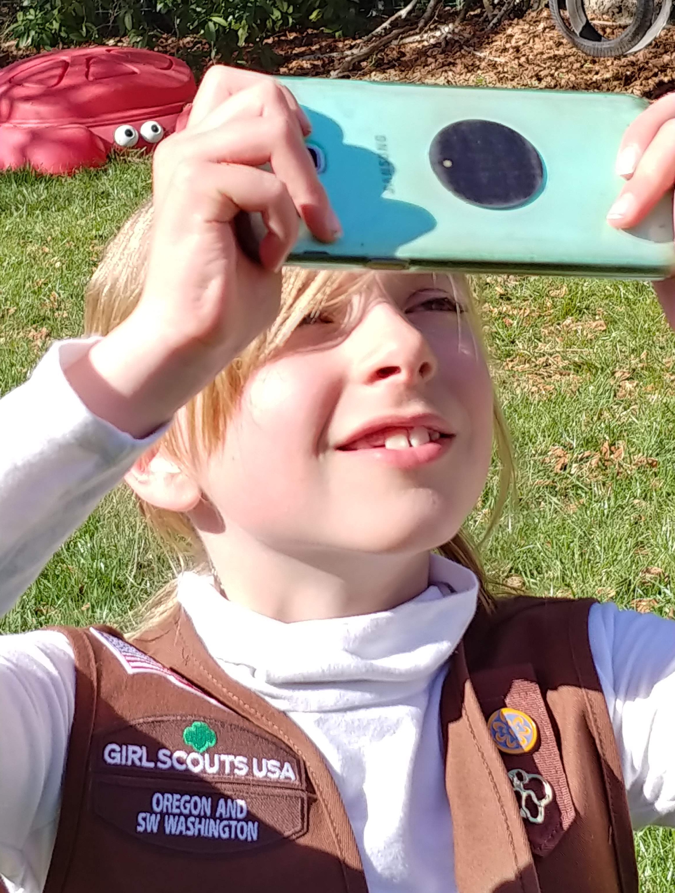 Girl Scout using a cell phone to take an observation with the GLOBE Observer app.