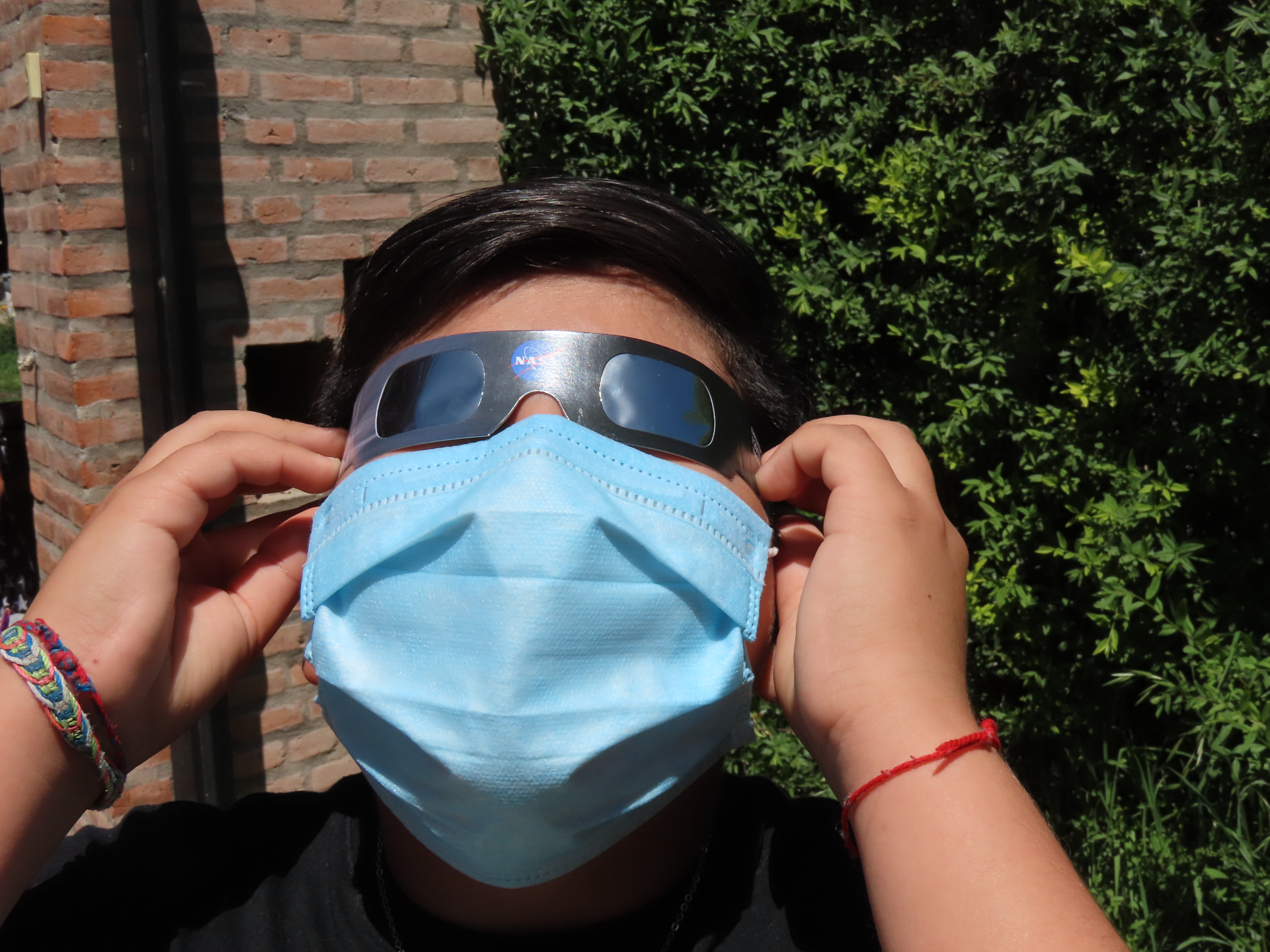 Person wearing solar viewing glasses and a face mask.