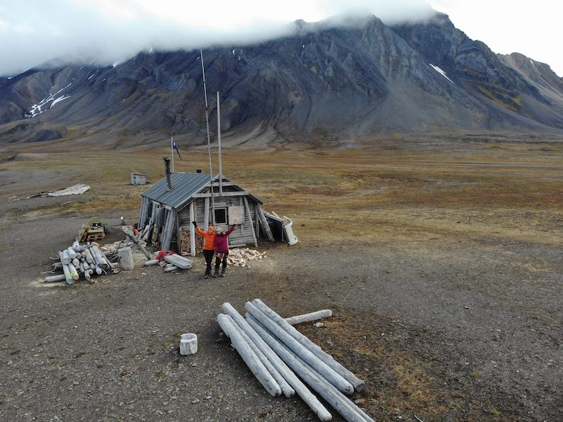 Hilde Fålun Strøm (left) and Sunniva Sorby (right) standing in front of the trapper cabin ‘Bamsebu’ in Svalbard, Norway.