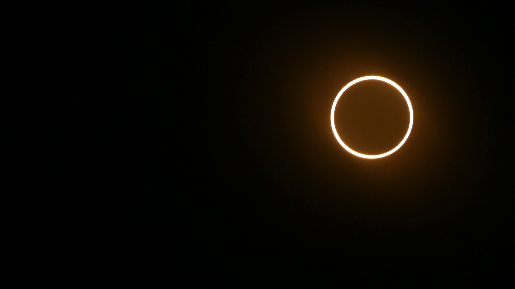 A dark background with the golden ring of an annular eclipse in the upper right corner. (Taken with a filter on a camera.)